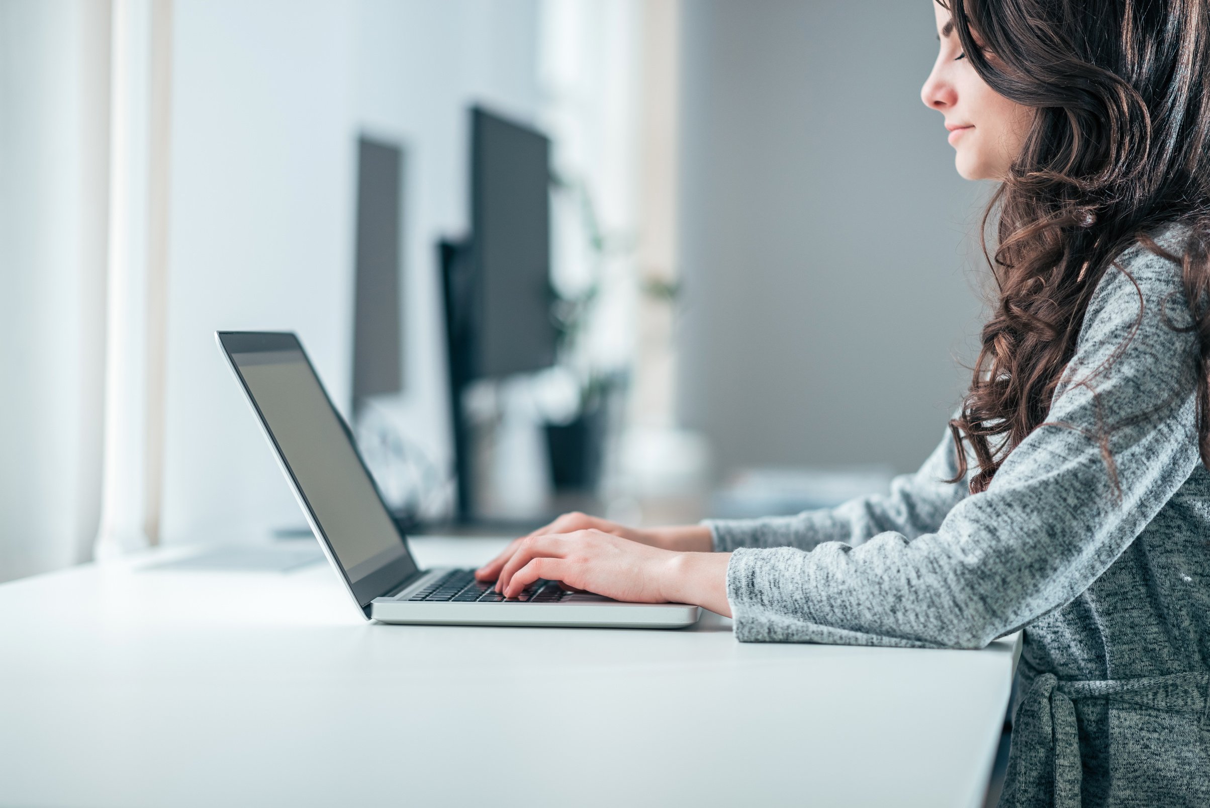 Young female administrative assistant working on laptop, side view.